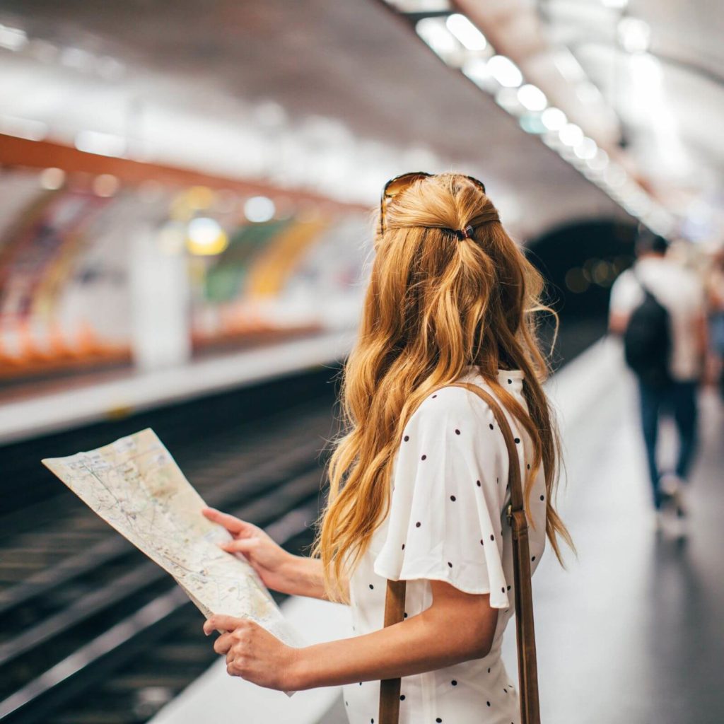 Photo of a woman at a metro station in Paris with a map in her hand.