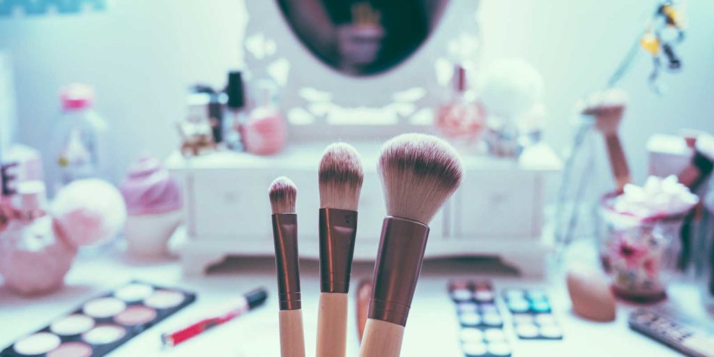 Closeup of a makeup brushes with a vanity in the background.