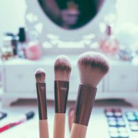Closeup of a makeup brushes with a vanity in the background.