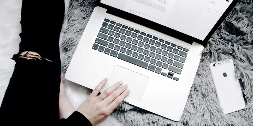 Closeup of a woman using a Mac laptop on top of a faux fur rug
