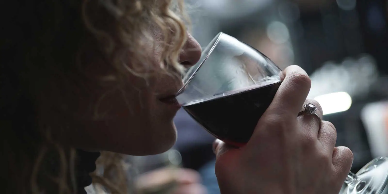 Closeup photo of a woman drinking a glass of red wine