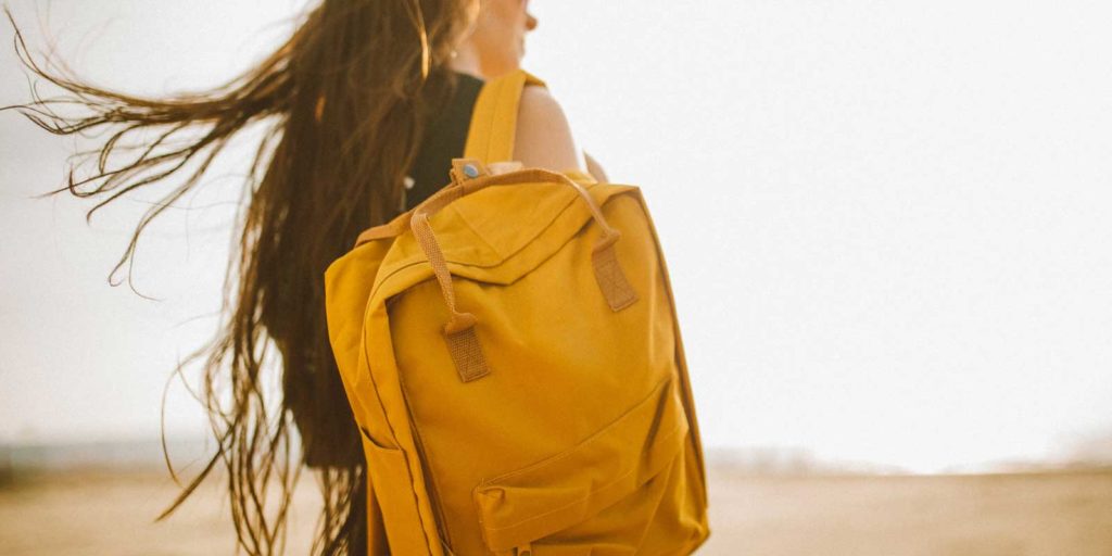 Close up of a woman carrying a mustard yellow backpack