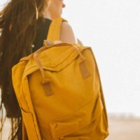 Close up of a woman carrying a mustard yellow backpack