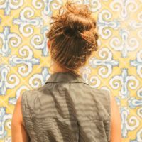 Woman looking at yellow, white and blue Spanish tiles on a wall.