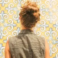 Woman looking at yellow, white and blue Spanish tiles on a wall.