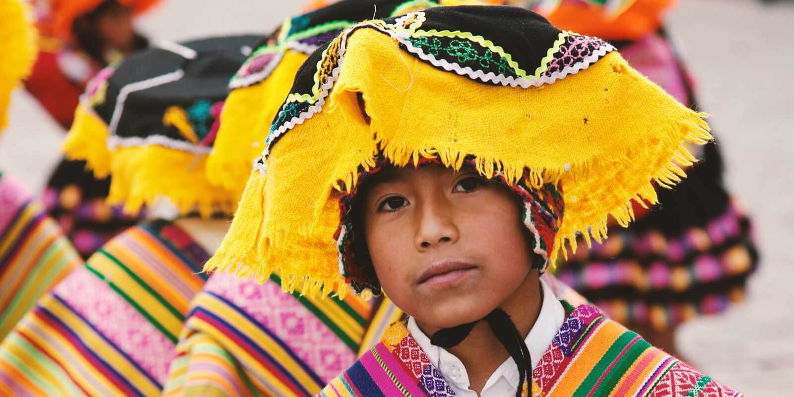 Closeup of a Peruvian child wearing colorful woven hat and clothing.