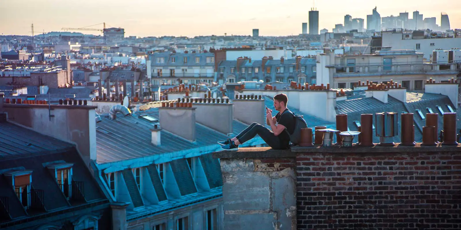 Man sits on the rooftop of a building in Paris.