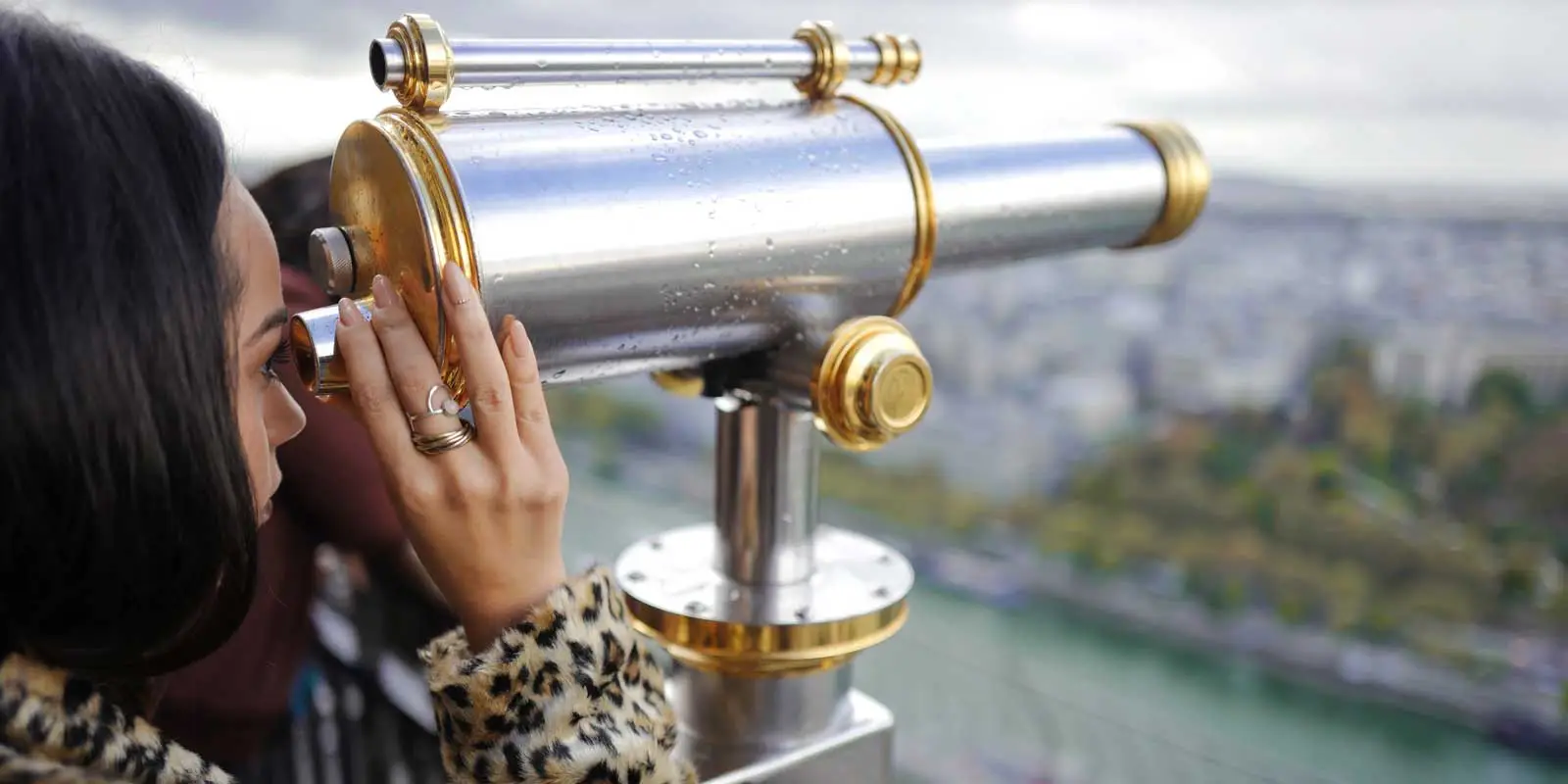 Woman looking through a telescope from the Eiffel Tower.