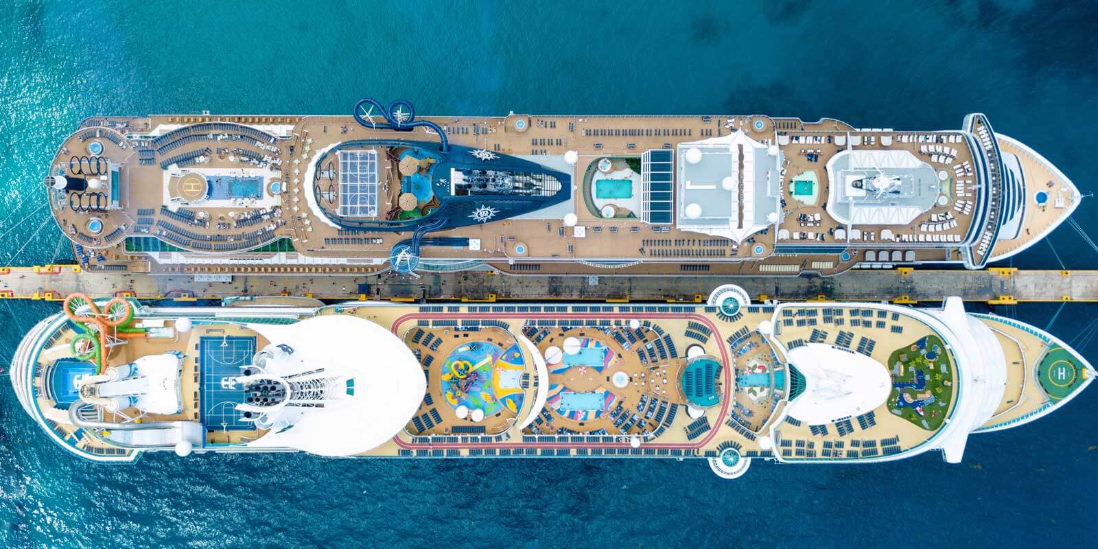 Aerial view of 2 cruise ships docked side by side.