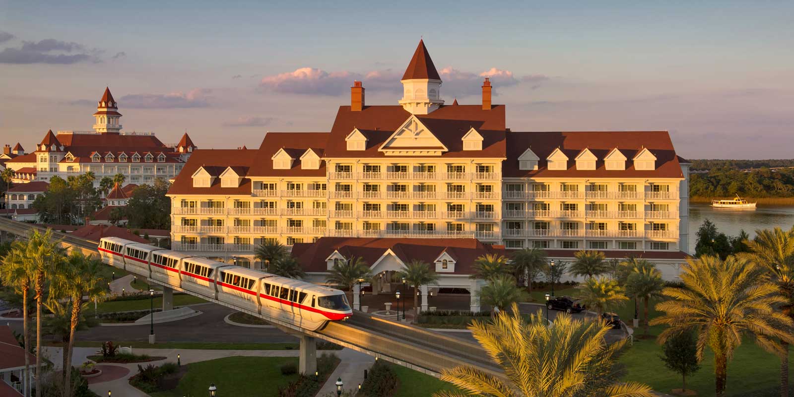 Landscape view of Grand Floridian resort at Disney World with the monorail in front and water at back.