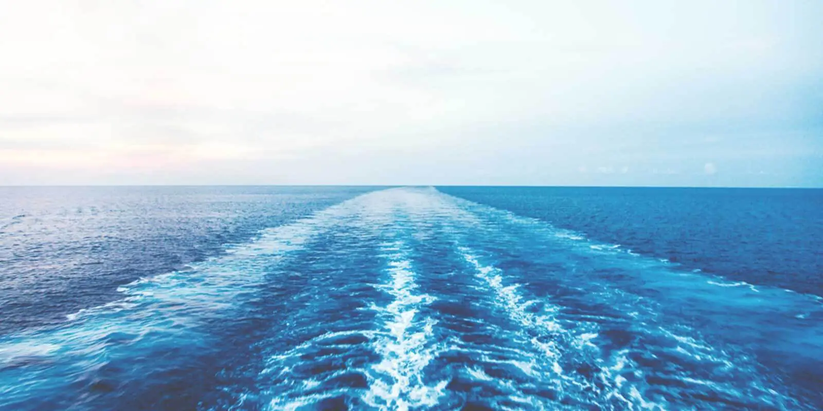 Landscape view of an open ocean with the wake trail from a cruise ship.