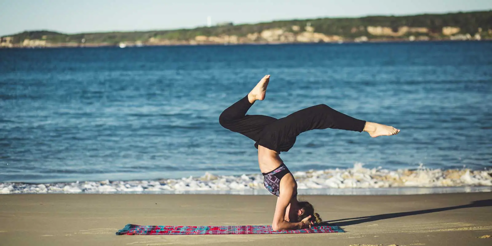 Woman doing yoga on an ocean beach.
