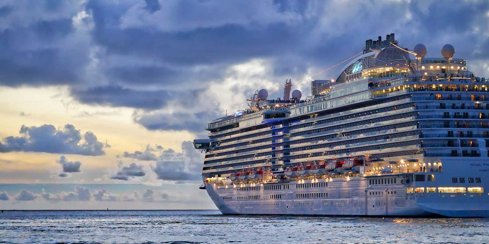 Landscape view of a gigantic vacation cruise ship at sunset.