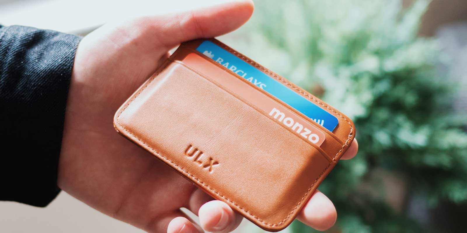 Man holding a small brown wallet with 2 credit cards in it.