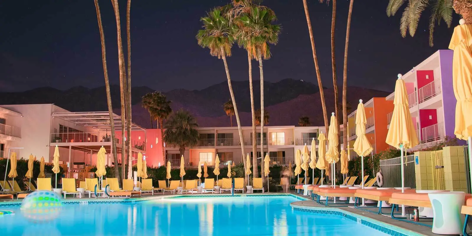 Nighttime landscape shot of a colorful hotel from its pool area.