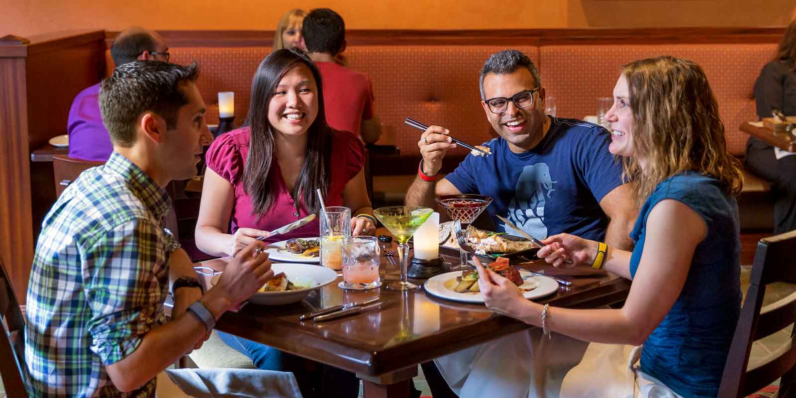 A group of adults enjoy a meal at Animal Kingdom's Tiffins restaurant.