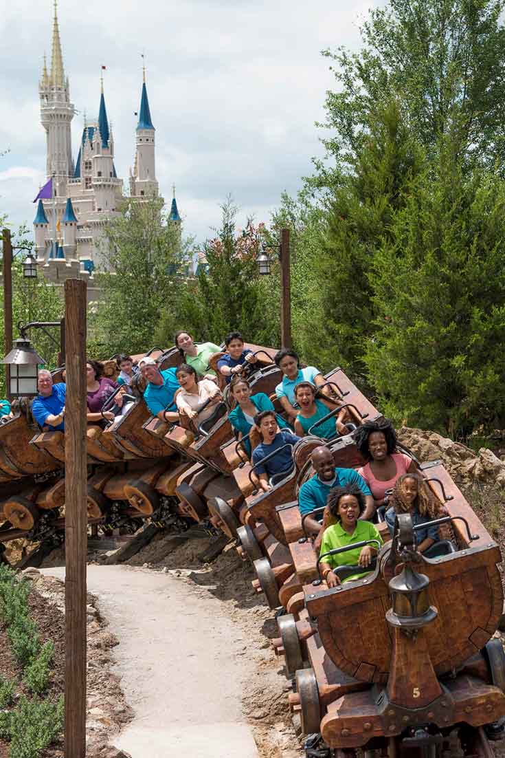 A group of people zip around a corner on the Seven Dwarfs Mine Train at Disney World's Magic Kingdom.