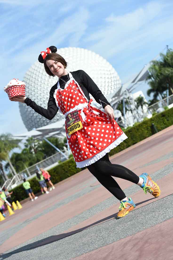 Woman dressed as Minnie Mouse and running sneakers poses in front of the Epcot sphere.