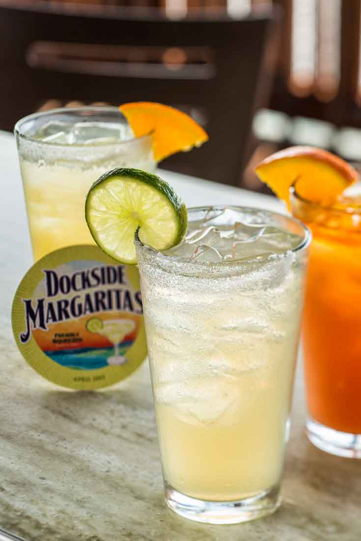 Closeup of 3 margaritas in tall glasses and a coaster from Dockside Margaritas.