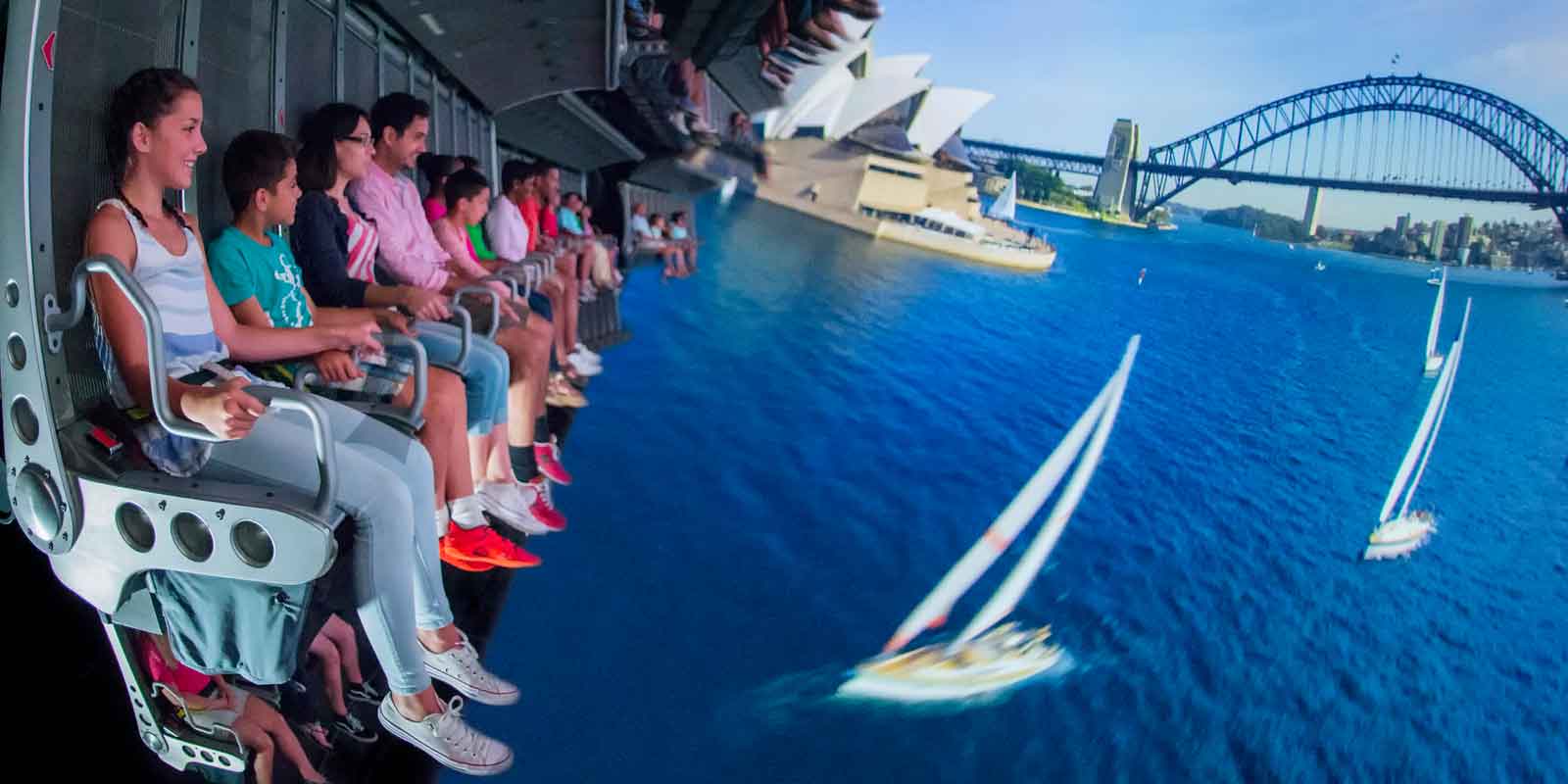 A group of people suspended in air in front of a massive virtual reality screen for the Epcot ride, Soarin.