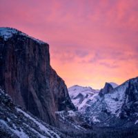 Landscape photo of a snow covered mountain in Yosemite National Park with pink skies in the backgrround.
