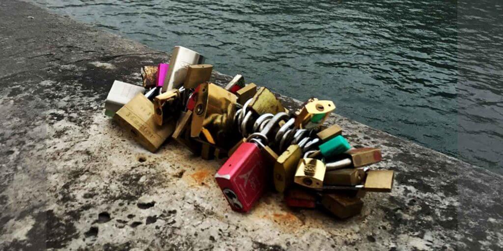 Close up photograph of a bunch of padlocks, also known as love locks, attached to a piece of a wall along the Seine River in Paris, France.