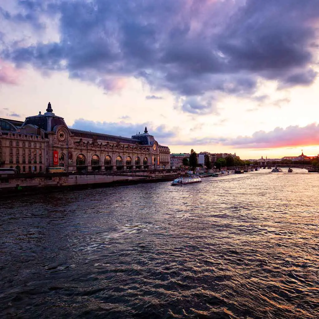 Landscape view of the Seine River in Paris during sunset with Musée d'Orsay in the background.