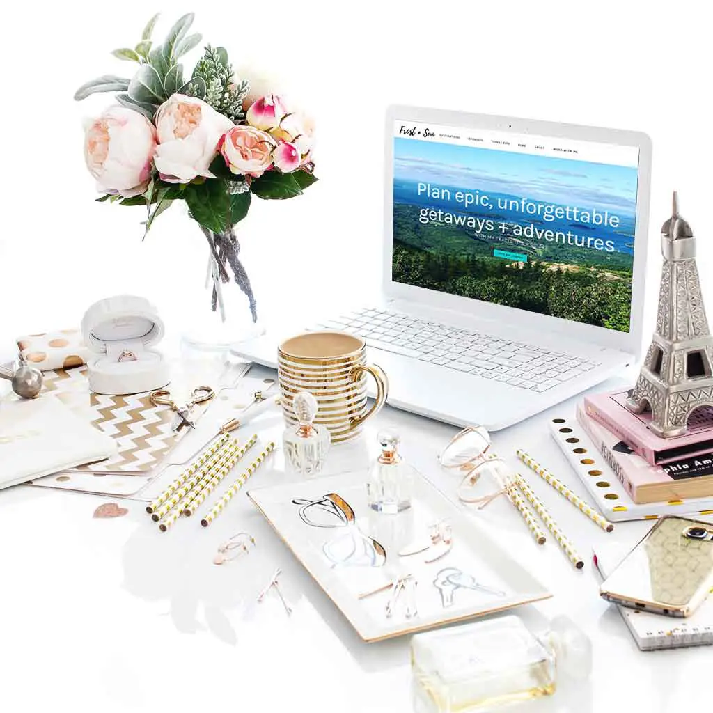Landscape view of a white desk with lots of gold and pink accessories, including an Eiffel Tower replica, and a laptop open to Frost + Sun website.