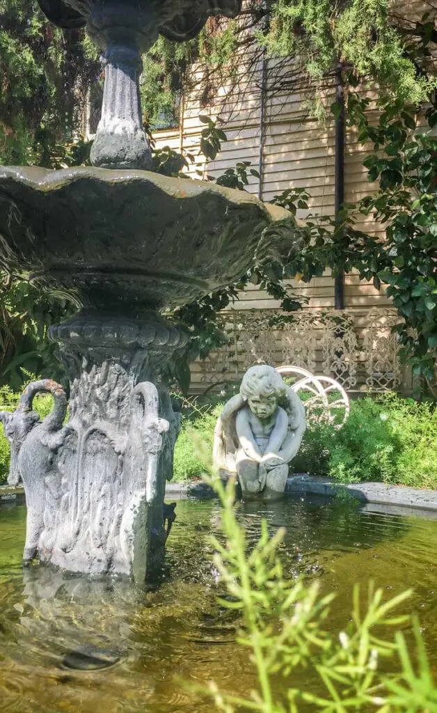 Closeup of a water fountain outside the Cornstalk Hotel, with a sullen cherub statue in the background.