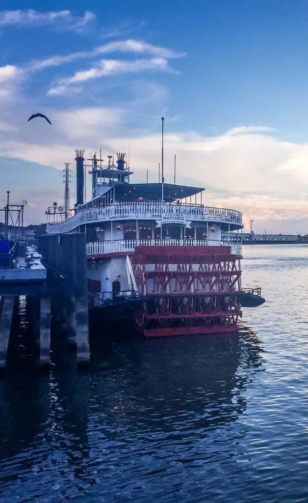 Photo of a paddleboat in the Mississippi River during sunset with dusky blue skies.