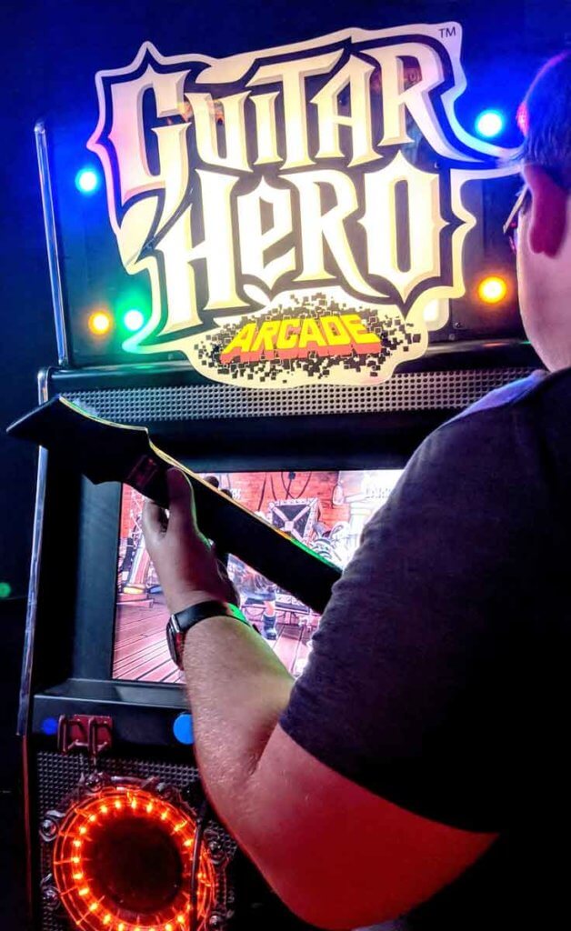 Closeup of a man playing Guitar Hero at an arcade.