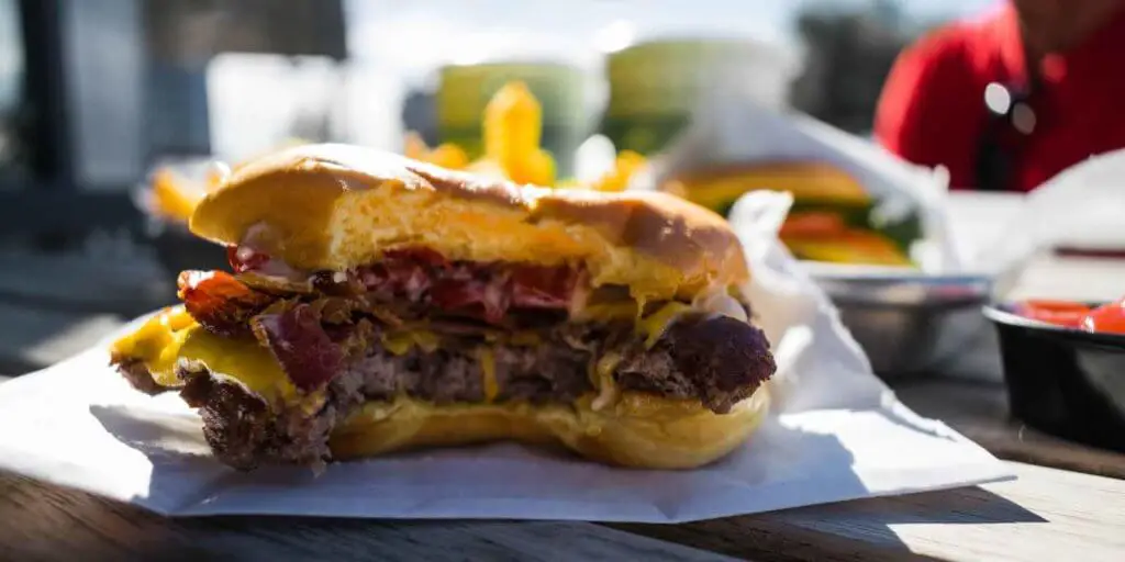 Close up shot of a half eaten bacon cheeseburger from Shake Shack.