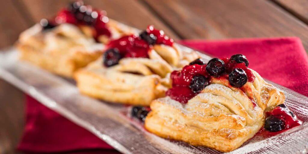 Closeup photograph of mini cheese strudels with berries spooned on top.