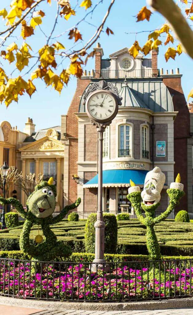 Photo of 2 topiaries, 1 shaped like Cogsworth and 1 shaped like Lumiere, characters from Beauty & the Beast.