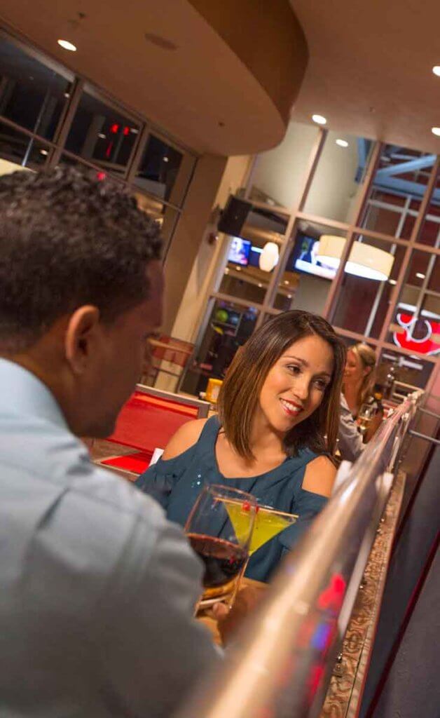 A couple enjoys a glass of wine and a cocktail on the outdoor patio at Splitsville Disney Springs.