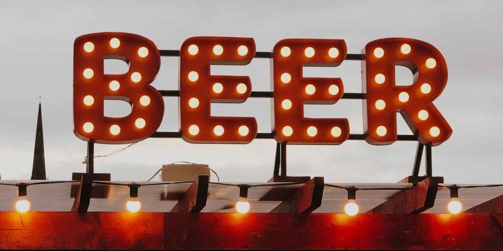 Close up of a large sign with red letters and lightbulbs spelling out BEER.