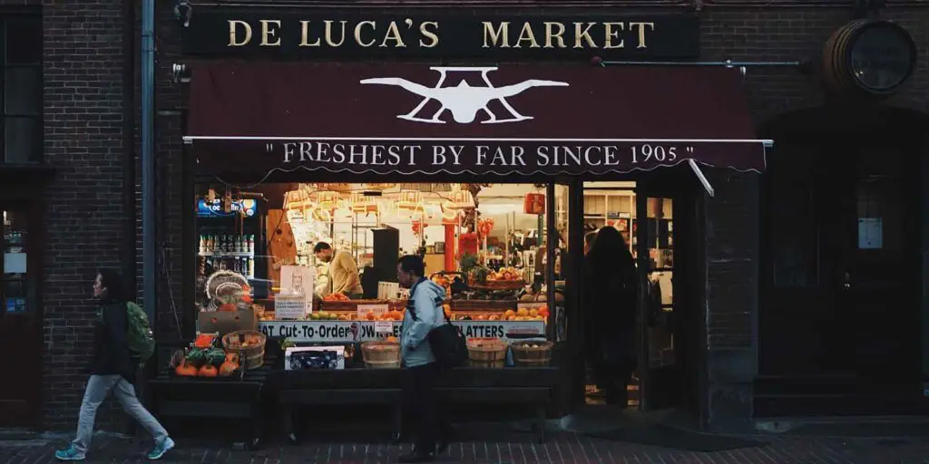 Landscape photo of the storefront for De Luca's Market on Newbury Street in Boston, MA, USA.