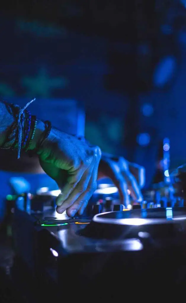 Closeup of a man using DJ turntables in the dark.