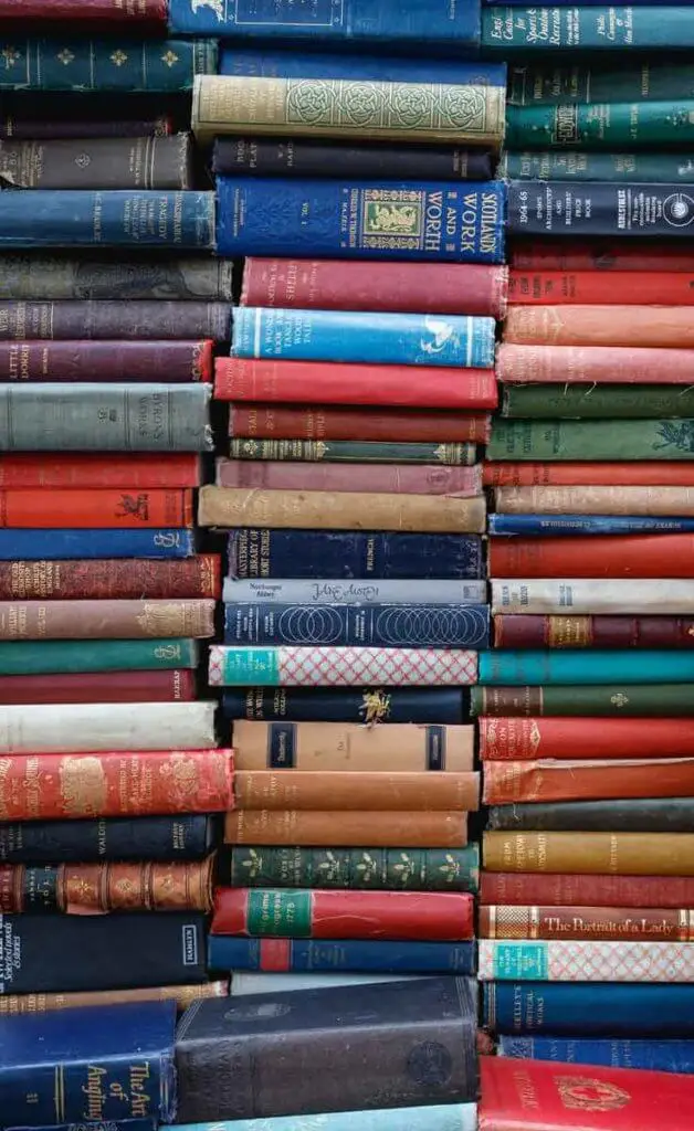 Close up of vertical stacks of vintage books in a variety of colors like red, navy blue, forest green, tan, and more.