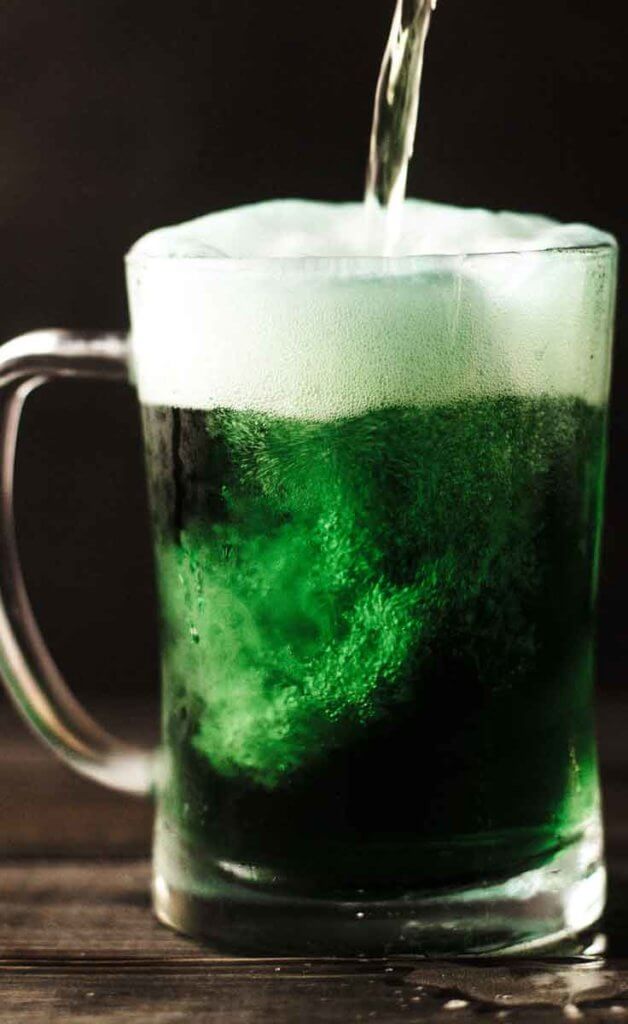 Close up photograph of a mug of green beer being poured.