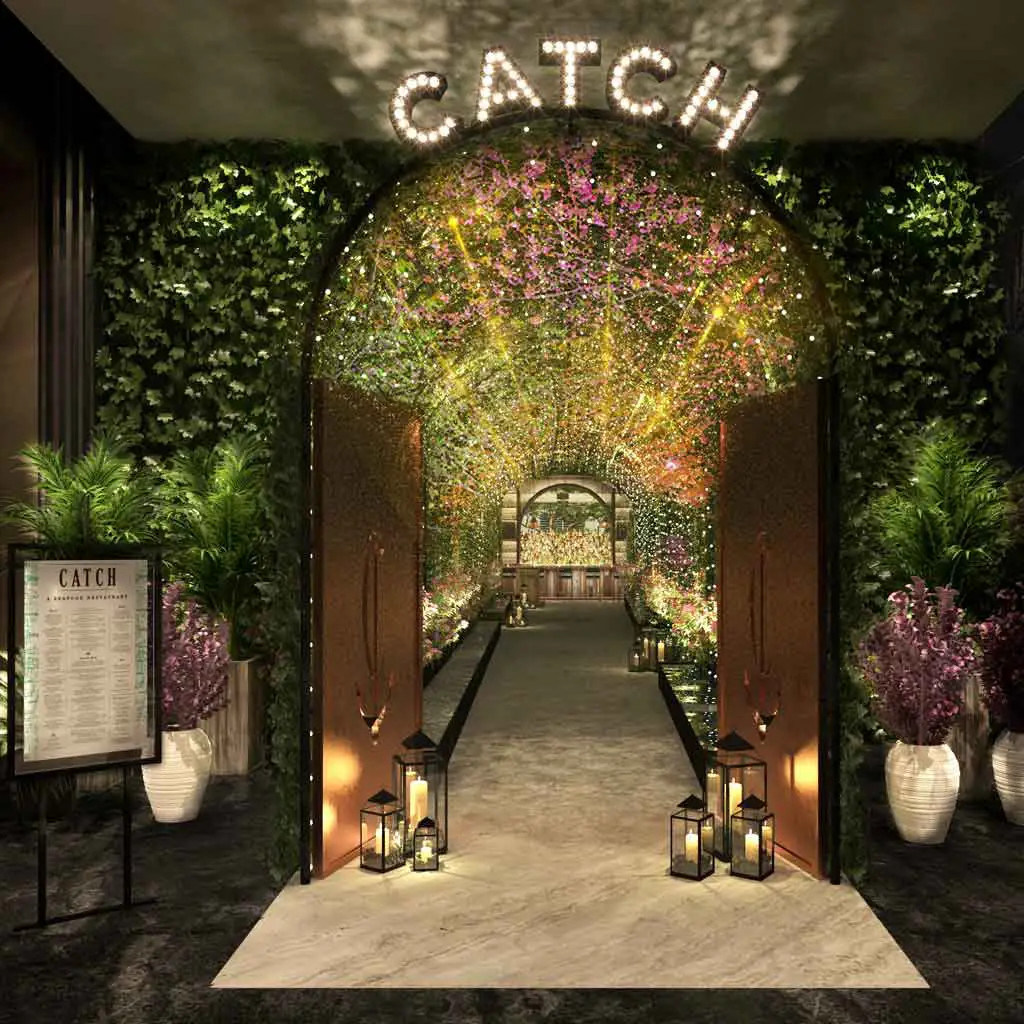 Photograph of the entrance to Catch Las Vegas, complete with twinkling lights, towering plants, and purple flowers.
