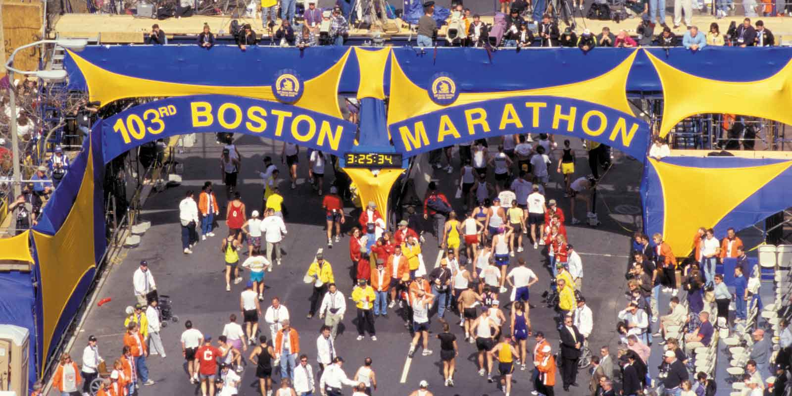 Landscape view of race route for the Boston Marathon with a blue and yellow sign that reads "103rd Boston Marathon."