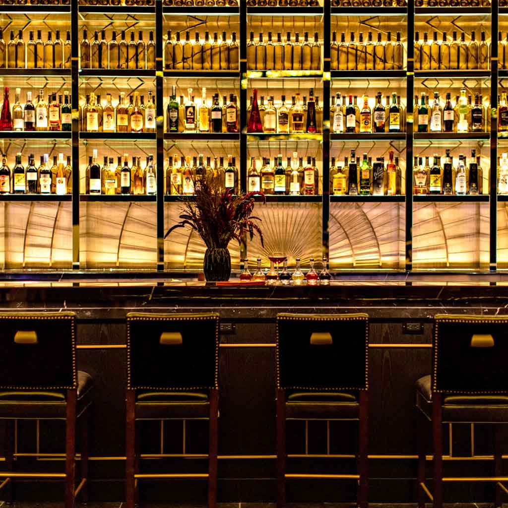 A closeup of the NoMad Bar in Las Vegas with dark furnishings and gold accents.