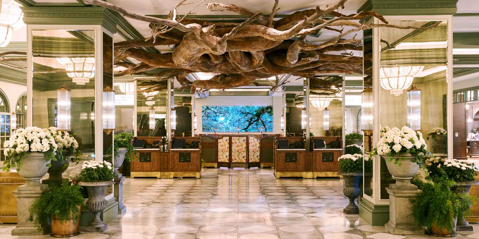 Landscape view of the hotel lobby at Park MGM with plants, white potted flowers, and a ceiling sculpture that resembles tree roots.