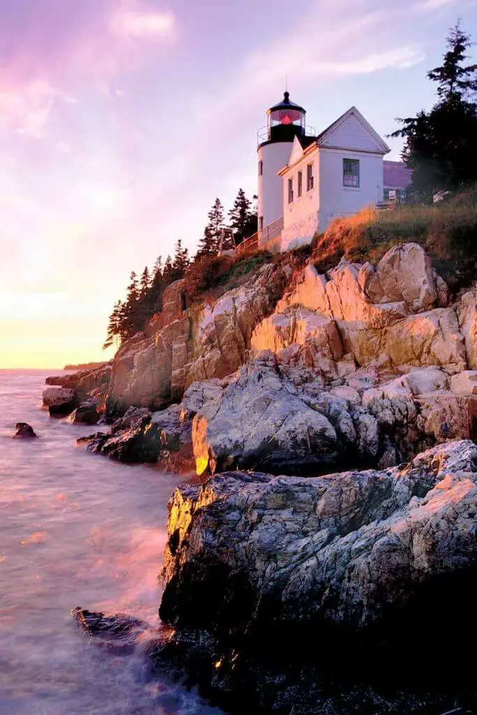 Photograph of the Bass Harbor Head Lighthouse on a rocky cliff during sunset.