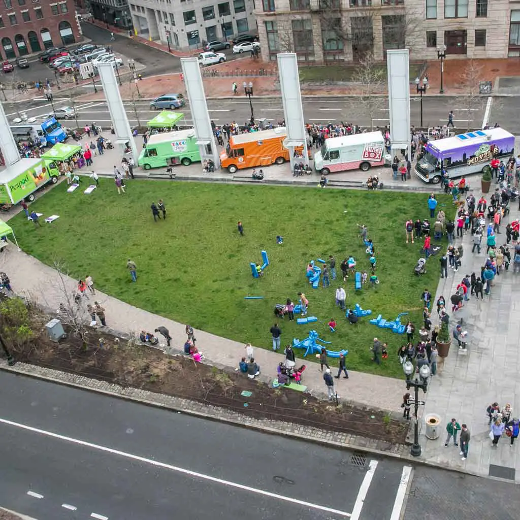 Aerial view of the greenway park in Boston, with 5 food trucks lining the outside of one section of the park.