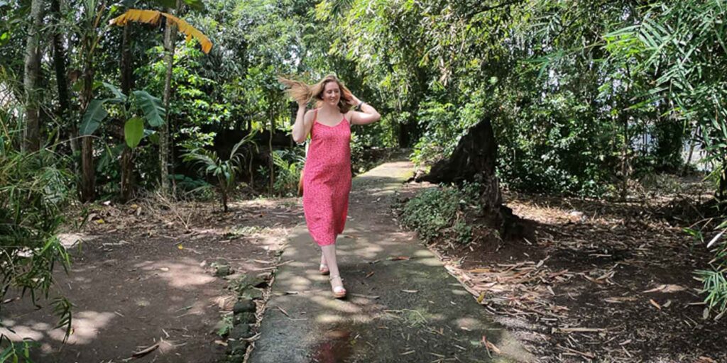 A woman flipping her hair while walking down a cement path in a tropical setting