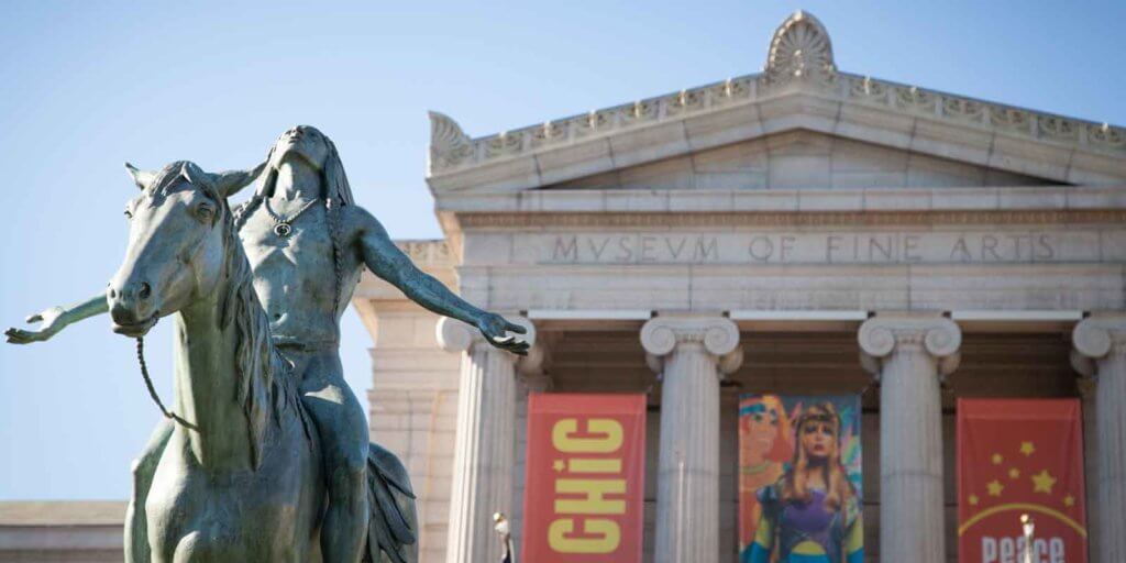 Closeup of a statue with the Museum of Fine Arts in the background.