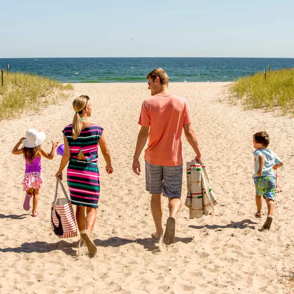 Photo of a family with 2 children walking toward the ocean at Hampton Beach, NH, one of many fun beaches available on a day trip from Boston.
