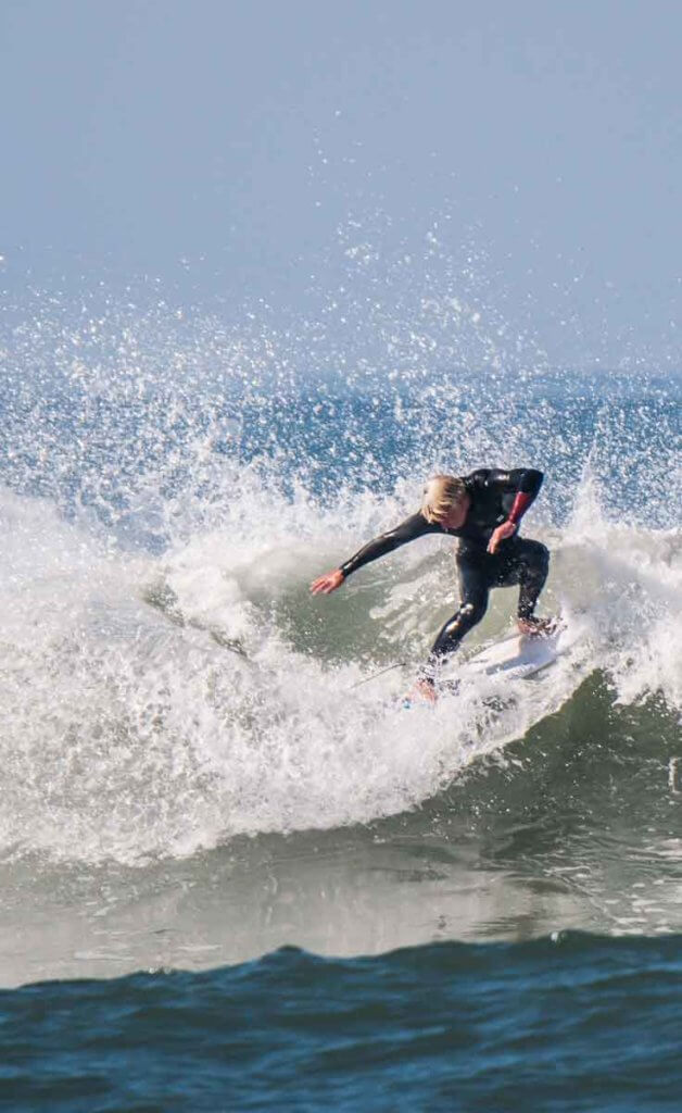 Man in a black wetsuit surfing a big wave in Surf City USA, aka Huntington Beach, California.